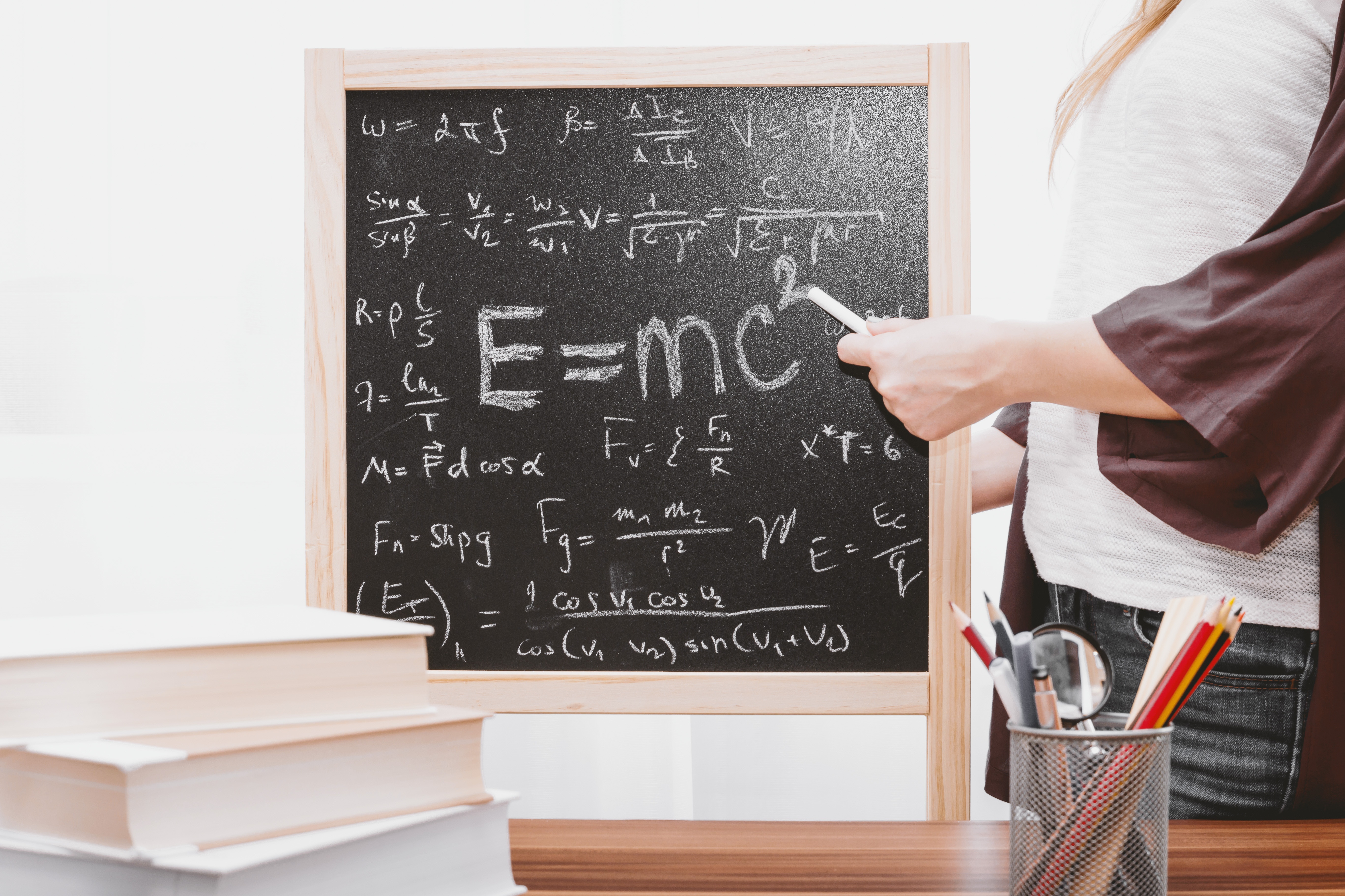 Teacher writing math formulas on small chalkboard